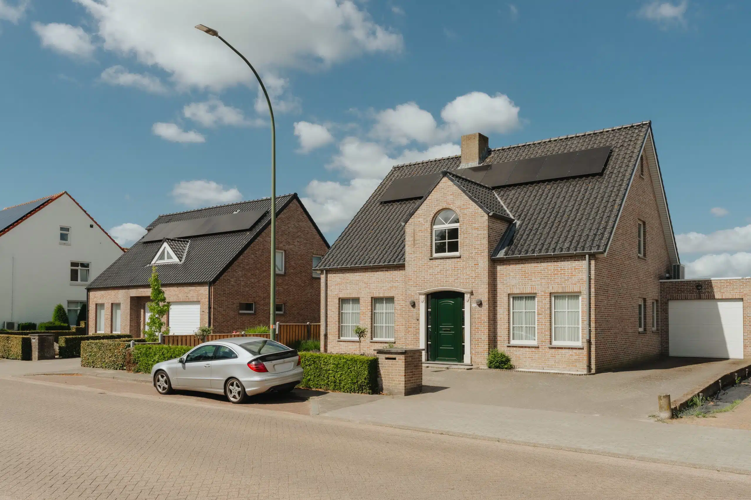Moderne bakstenen villa met groene deur en oprit in Nederlandse woongemeente