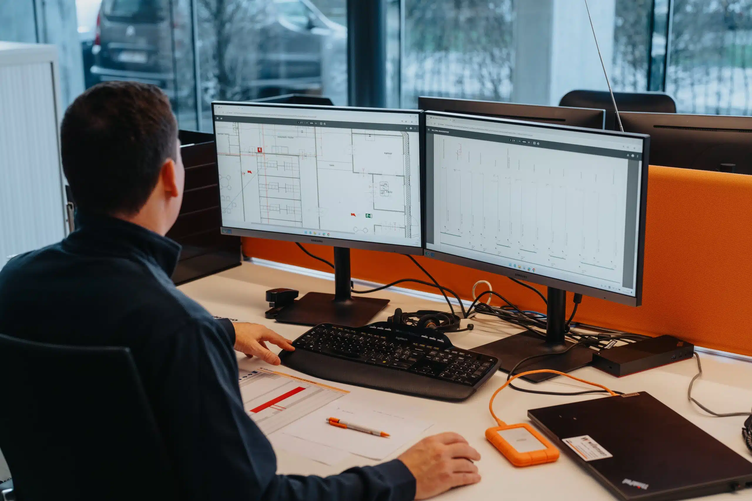 Technicus van Willemsen Technieken bestudeert laadpaal installatieplan op dual monitors in kantoor Arendonk