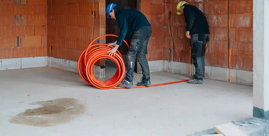 Willemsen Technieken installateurs leggen oranje electriciteitskabel in nieuwbouw voor sanitair- en verwarmingsinstallatie