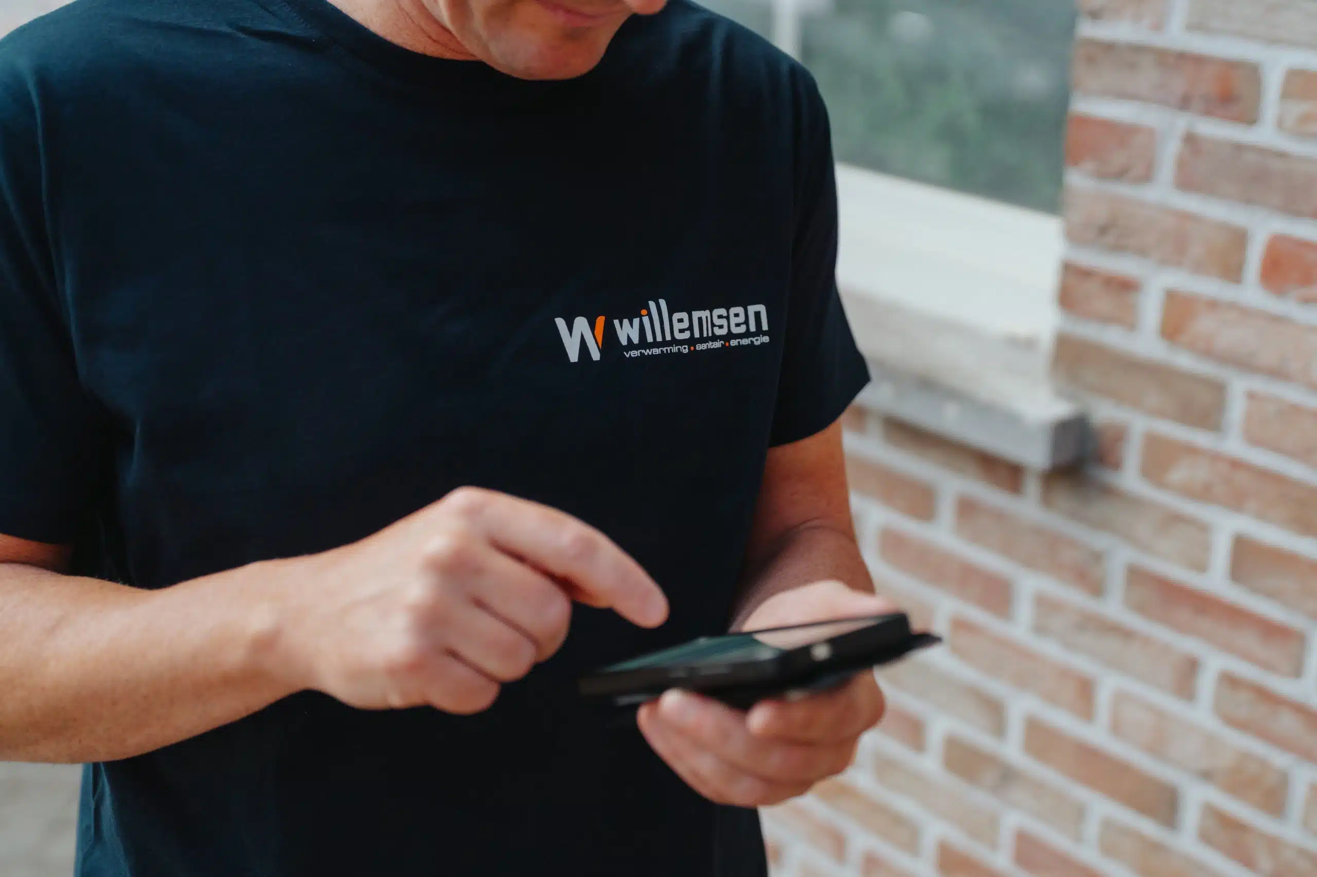 Willemsen Technieken technicus controleert laadpaal installatie op smartphone in Arendonk