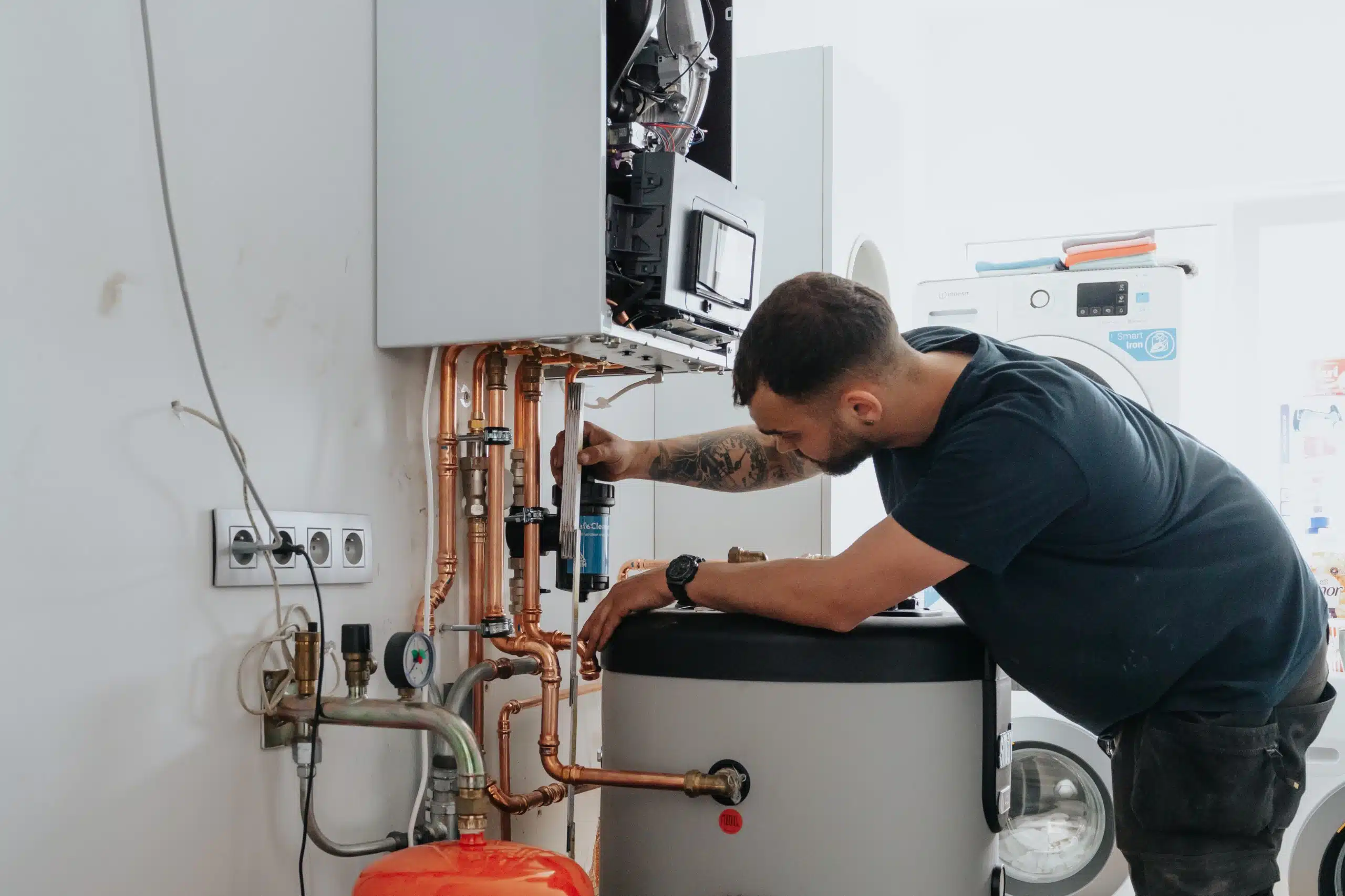 Verwarming installatie technicus installeert warmwaterbuffer met gasketel en koperen buizen
