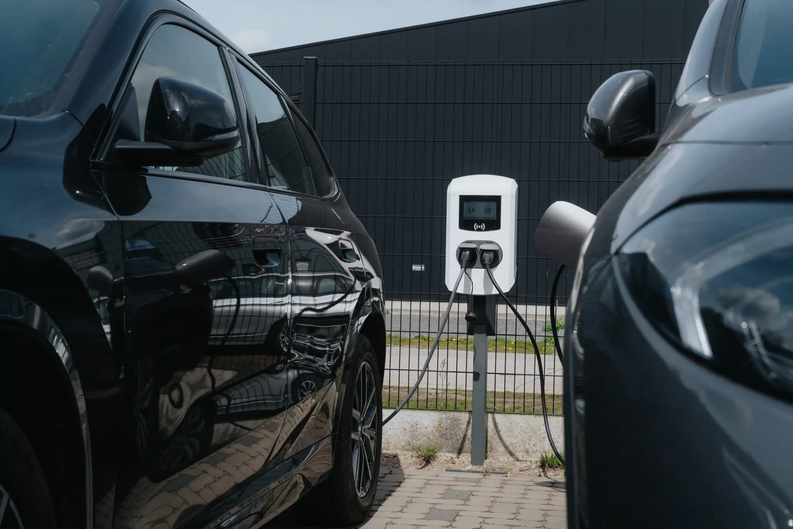 Twee elektrische auto's laden op een Willemsen laadpaal thuis in Belgiƫ met draadloze verbinding en digitaal display